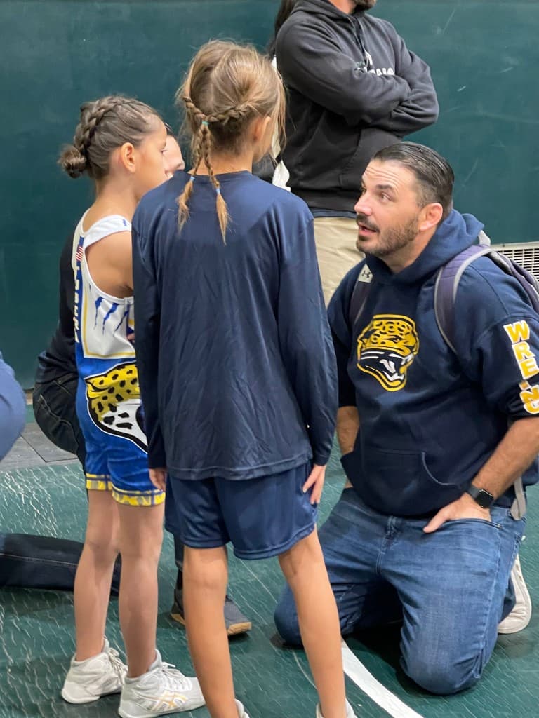 Adam Lancaster, founder of Next Level Athlete Network, with young wrestlers on the mat